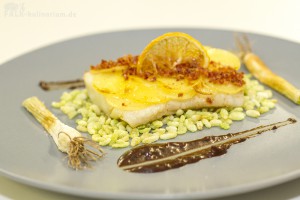 Pannfisch - Ostseedorsch unter der Kartoffelhaube mit Ofenlauch und Speckstaub mit schwarzer Senfsauce auf grünem Knuspereis